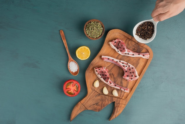 Mujer sosteniendo cuenco de especias y trozos de carne cruda en el cuadro azul.