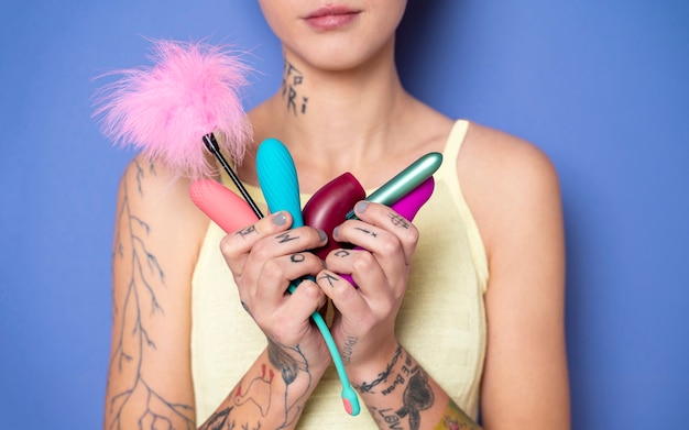 Mujer sosteniendo diferentes juguetes sexuales vista frontal