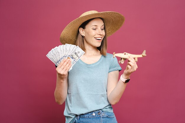 Mujer sosteniendo dinero y avión de madera