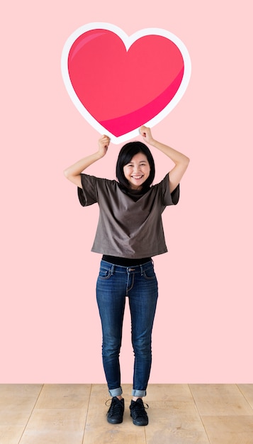 Mujer sosteniendo un emoticon de corazón en un estudio