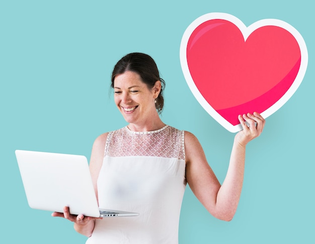 Mujer sosteniendo un emoticon de corazón y una laptop