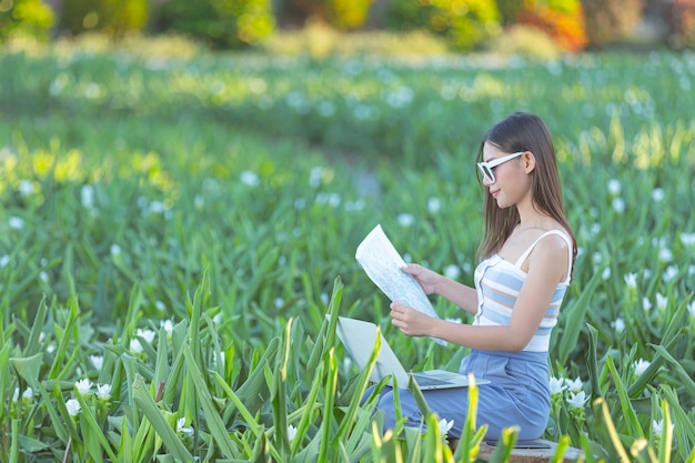 Mujer sosteniendo felizmente un mapa turístico en el jardín de flores