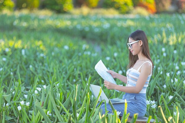 Mujer sosteniendo felizmente un mapa turístico en el jardín de flores