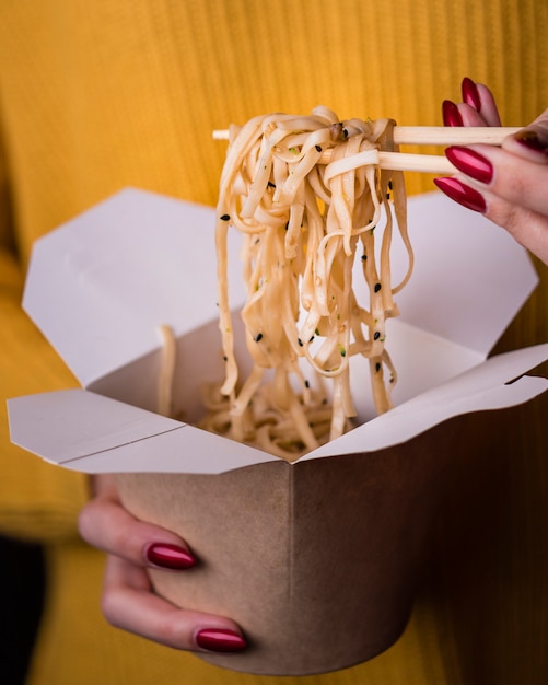 Mujer sosteniendo fideos en palillos