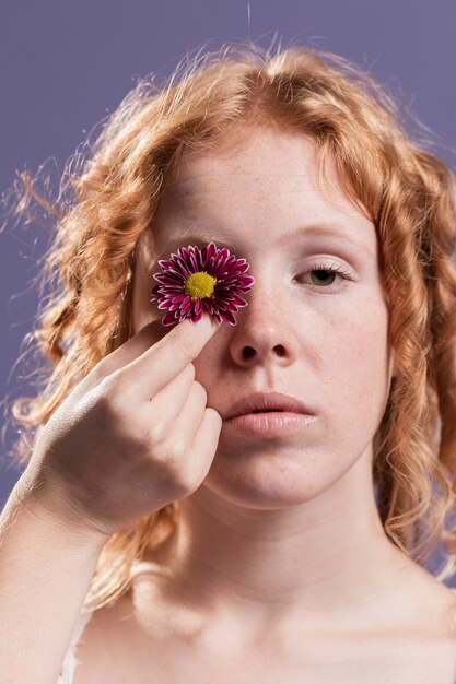 Mujer sosteniendo una flor sobre su ojo