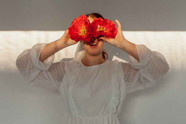 Mujer sosteniendo flores sobre los ojos