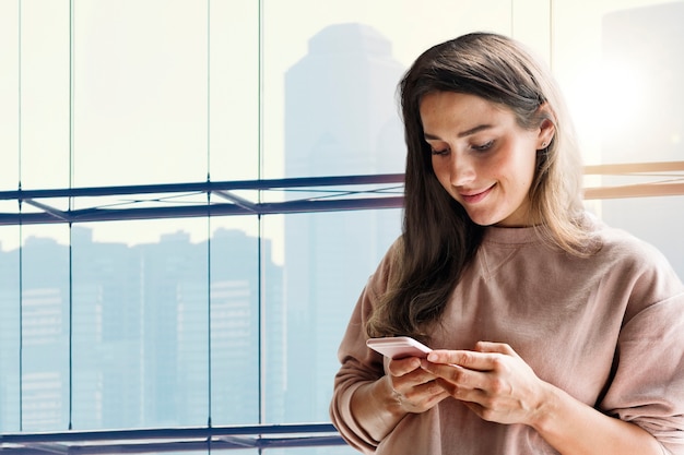 Mujer sosteniendo el fondo del teléfono inteligente en la nueva normalidad con medios remezclados de vista a la ciudad