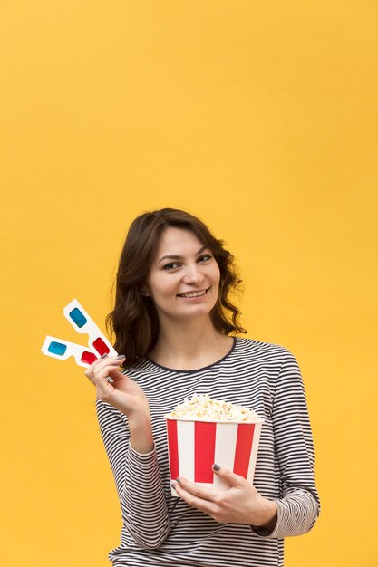 Mujer sosteniendo gafas 3d y un cubo con palomitas de maíz con espacio de copia