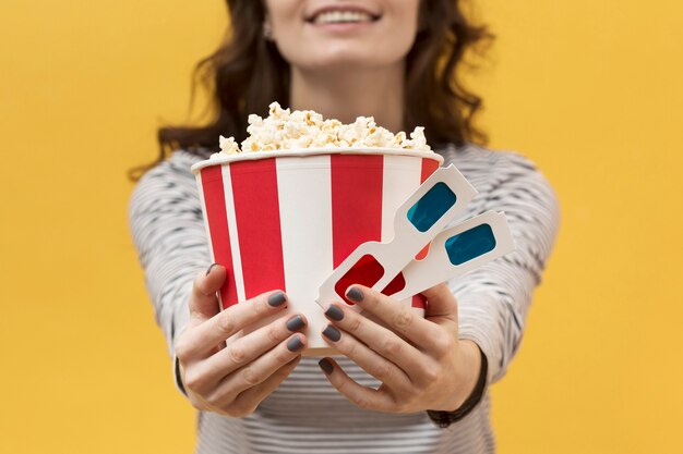 Mujer sosteniendo gafas 3d y un cubo con palomitas de maíz