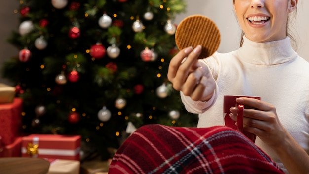 Mujer sosteniendo una galleta y una taza roja