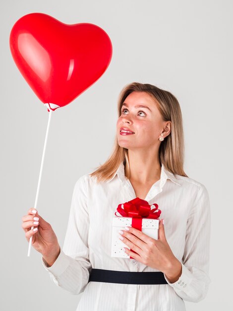 Mujer sosteniendo globos y regalos para San Valentín