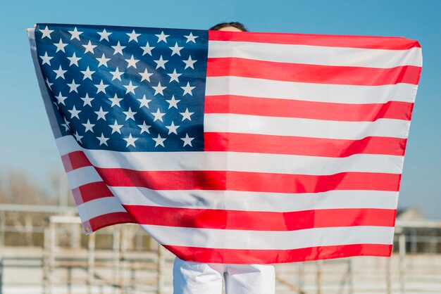 Mujer sosteniendo gran bandera de Estados Unidos sobre sí misma