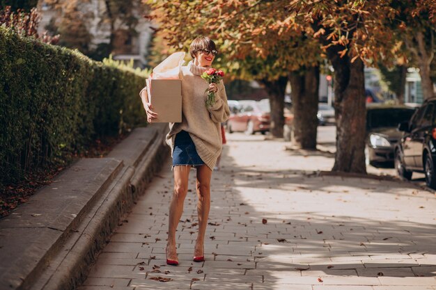 Mujer sosteniendo gran caja de paquetería y caminando en la calle