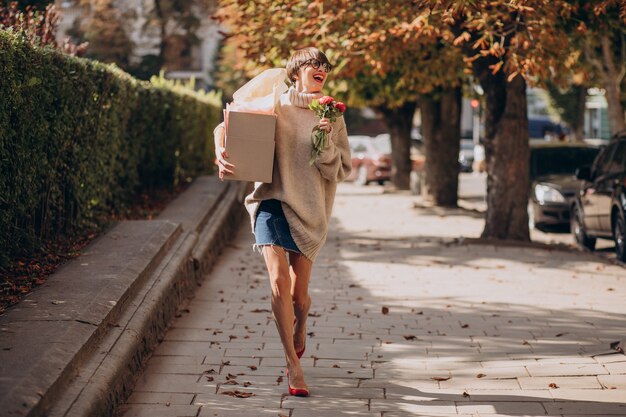 Mujer sosteniendo gran caja de paquetería y caminando en la calle