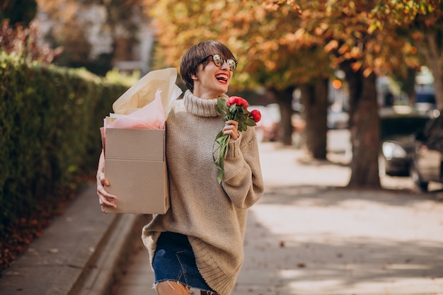 Mujer sosteniendo gran caja de paquetería y caminando en la calle