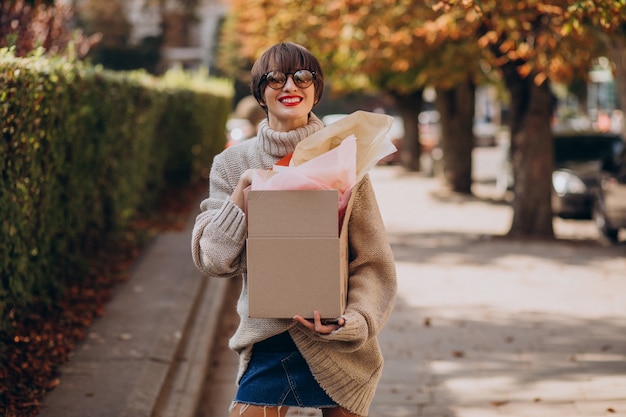 Foto gratuita mujer sosteniendo gran caja de paquetería y caminando en la calle