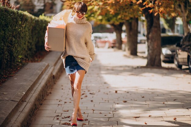 Mujer sosteniendo gran caja de paquetería y caminando en la calle