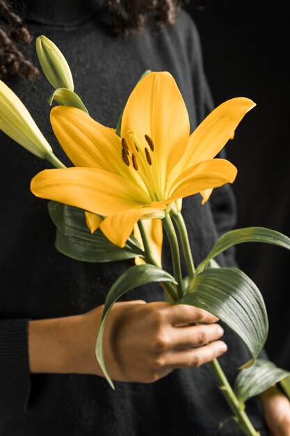 Mujer sosteniendo gran flor amarilla en las manos