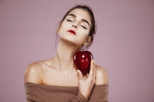 mujer sosteniendo gran manzana roja en rosa