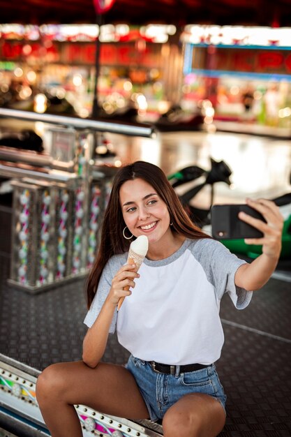 Mujer sosteniendo helado tomando selfie