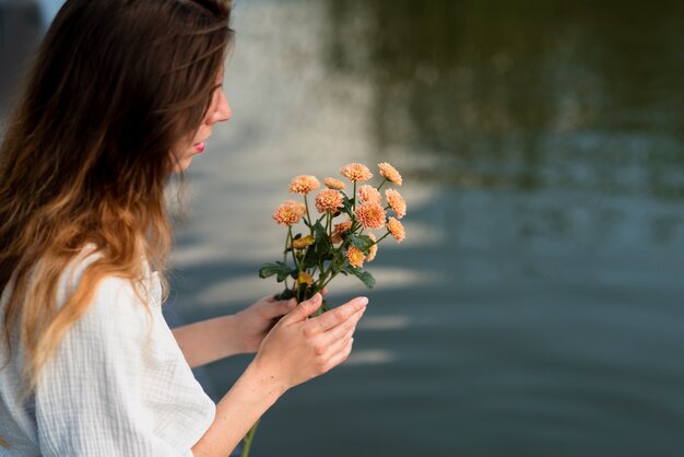 Mujer sosteniendo hermosas flores vista lateral