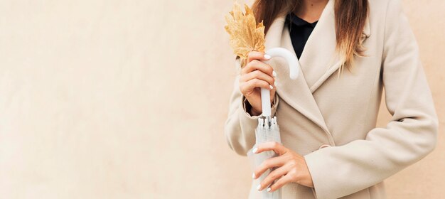 Mujer sosteniendo una hoja otoñal con espacio de copia