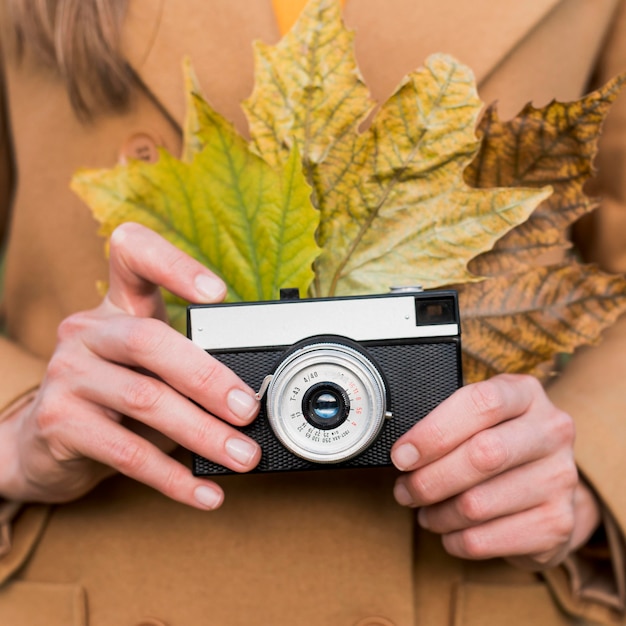 Mujer sosteniendo hojas de otoño y su cámara