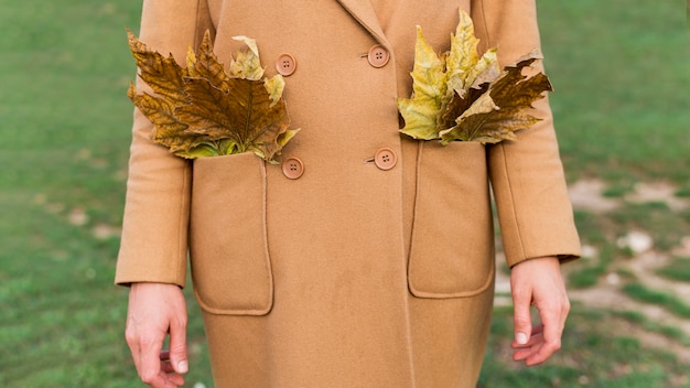 Foto gratuita mujer sosteniendo hojas de otoño en sus bolsillos