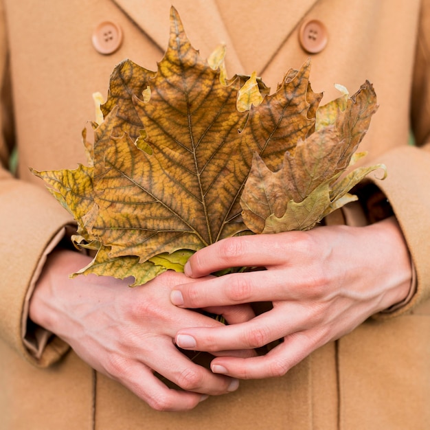 Mujer sosteniendo hojas de otoño