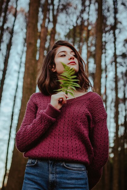 Mujer sosteniendo hojas posando en el bosque