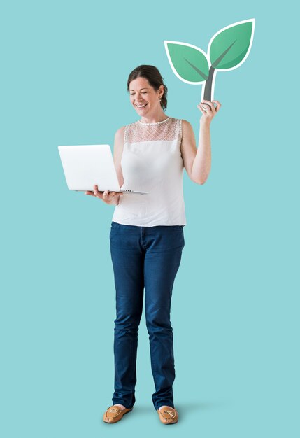 Mujer sosteniendo un icono de planta y usando una laptop