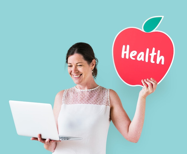 Mujer sosteniendo un icono de salud y usando una laptop