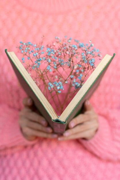 Mujer sosteniendo un libro abierto con un ramo de flores secas dentro