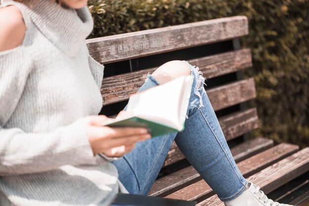 Mujer sosteniendo el libro y sentado en el banco