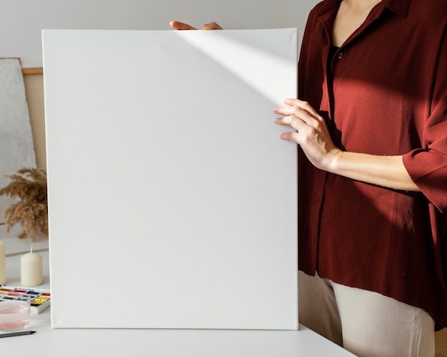 Mujer sosteniendo un lienzo en blanco