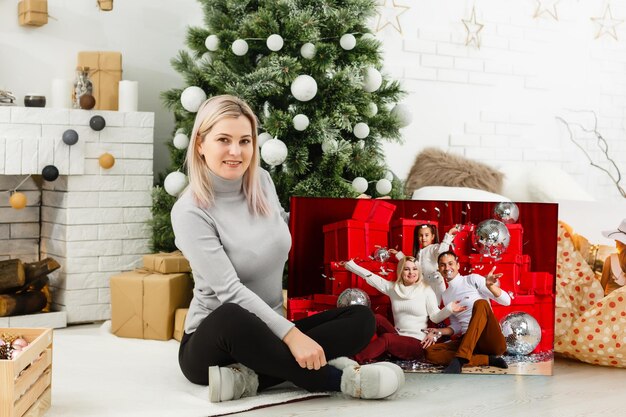 Mujer sosteniendo un lienzo fotográfico en el fondo de un interior navideño