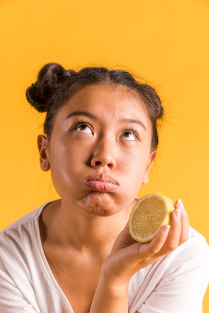 Foto gratuita mujer sosteniendo un limón y mirando a otro lado