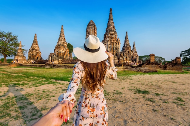 Foto gratuita mujer sosteniendo la mano del hombre y llevándolo al parque histórico de ayutthaya, el templo budista wat chaiwatthanaram en tailandia.