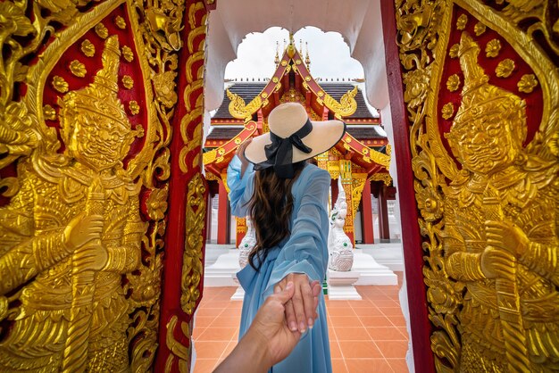 Mujer sosteniendo la mano del hombre y llevándolo a Wat Khua Khrae en Chiang Rai, Tailandia