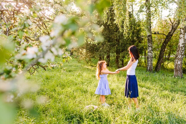 Mujer sosteniendo la mano de su hija en el parque