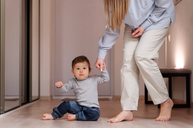 Mujer sosteniendo las manos de un niño en casa