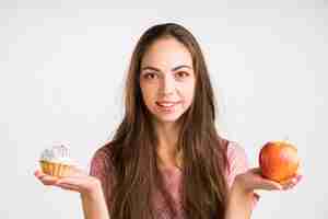 Foto gratuita mujer sosteniendo y manzana y un cupcake