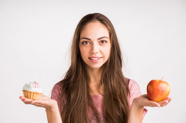 Mujer sosteniendo y manzana y un cupcake