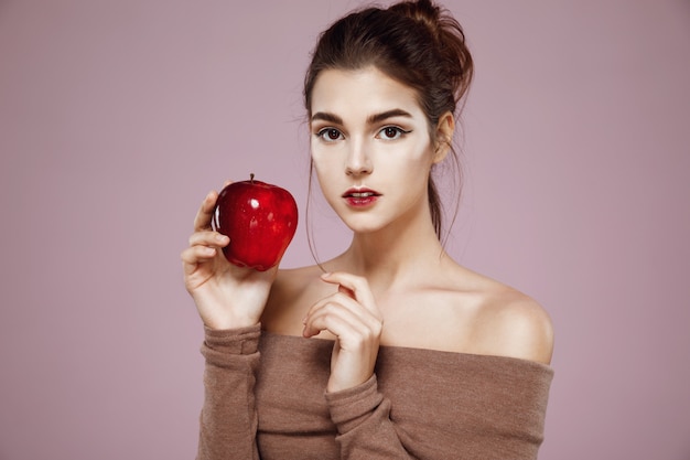 mujer sosteniendo manzana roja en rosa