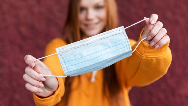 Mujer sosteniendo una máscara médica