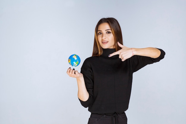 mujer sosteniendo un mini globo y encontrando ubicaciones en él.