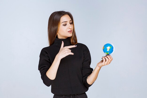 mujer sosteniendo un mini globo y encontrando ubicaciones en él.
