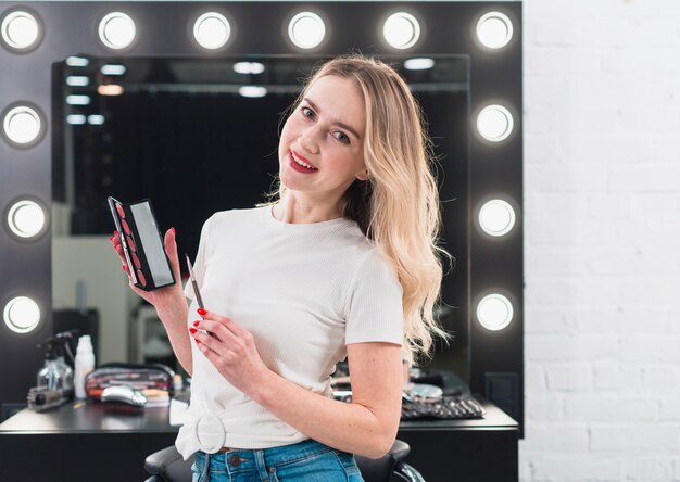 Mujer sosteniendo la paleta de colores con lápiz labial y pincel