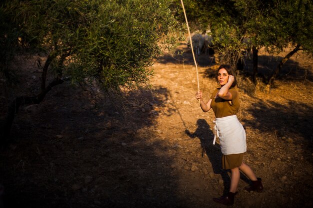 Mujer sosteniendo palos en la mano caminando en el campo