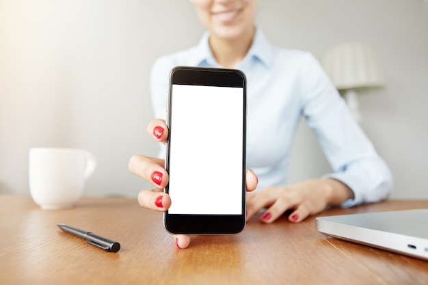 Mujer sosteniendo la pantalla del teléfono inteligente blanco en blanco